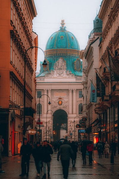 During the day, people walking on the streets of the brown concrete buildings nearby
